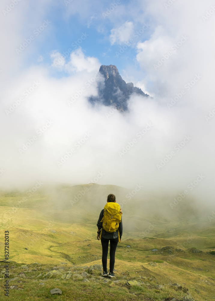Girl with backpack hiking, Midi d?Ossau peak in the background in the Pyrenees National Park, France.