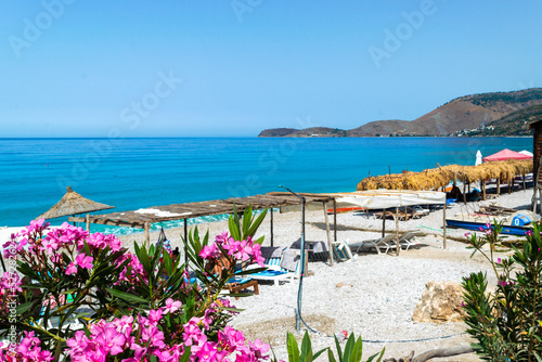 Vacationers on long Borsh beach with clear blue water. Cloudless sky. Albania. Ionian Sea