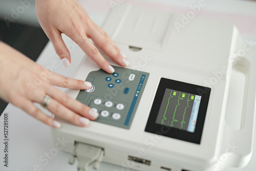 Woman cardiologist doctor makes electrocardiography procedure using cardiograph in modern clinic. photo