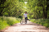 A woman with a bike on a road in the park
