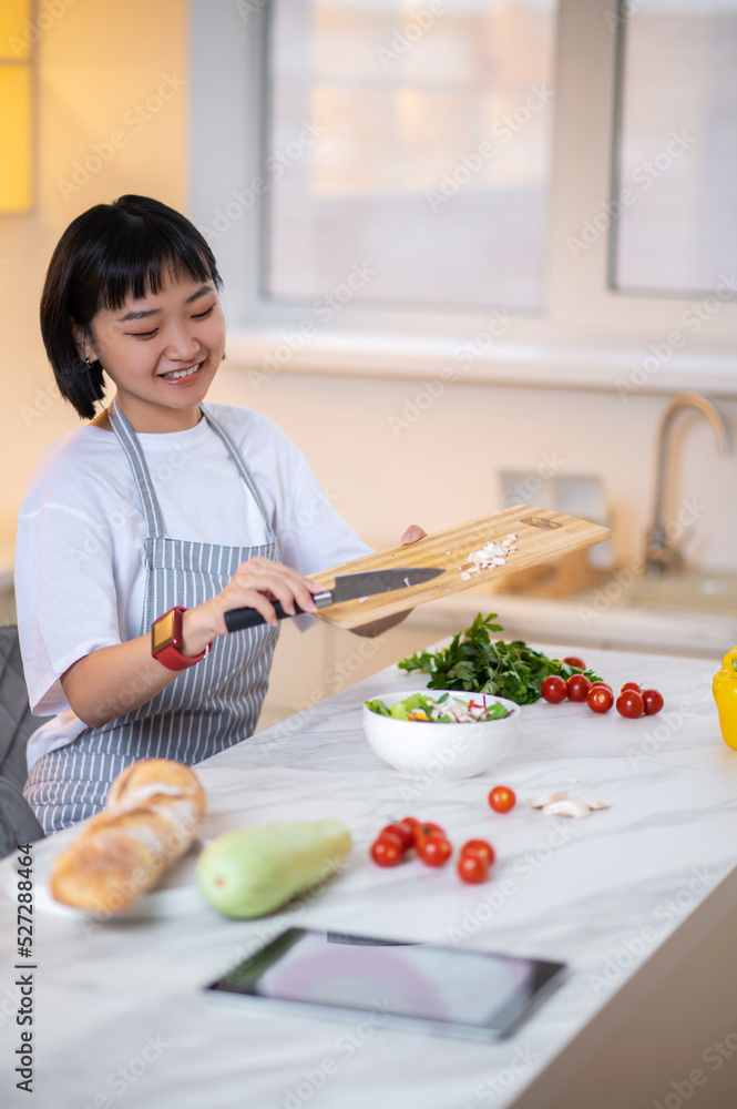 A woman making salad from fresh vegetables in the kitchen A woman making salad from fresh vegetables in the kitchen