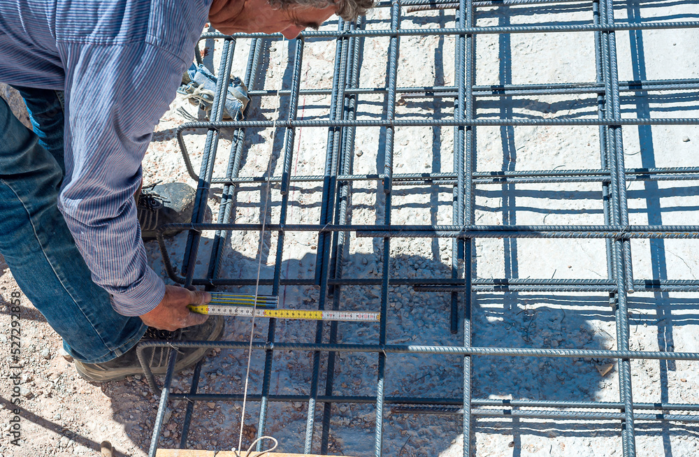 construction worker measuring distance of the foundation rebar in