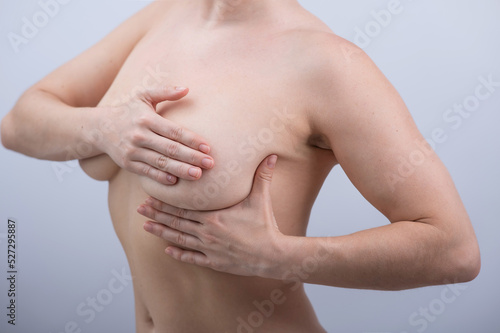 Caucasian woman self checks for breast cancer on white background. 