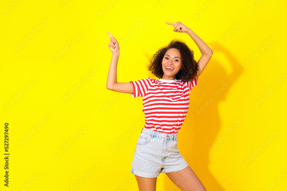 Naklejka premium Portrait of young attractive happy woman directing empty space summer clothes shop isolated on yellow color background