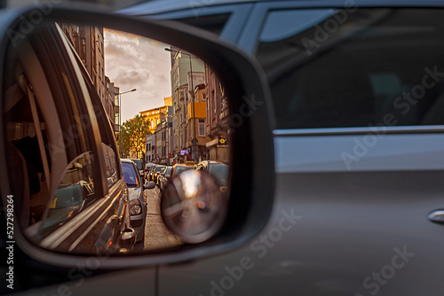 reflection of huge traffic in the right car mirror in the evening at sunset in a city of millions. Traffic.
