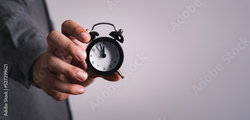 Fototapeta Naklejka Na Ścianę i Meble -  The hand of  businessman man holds the alarm clock. The Concept of Time to work,punctual on time or late.