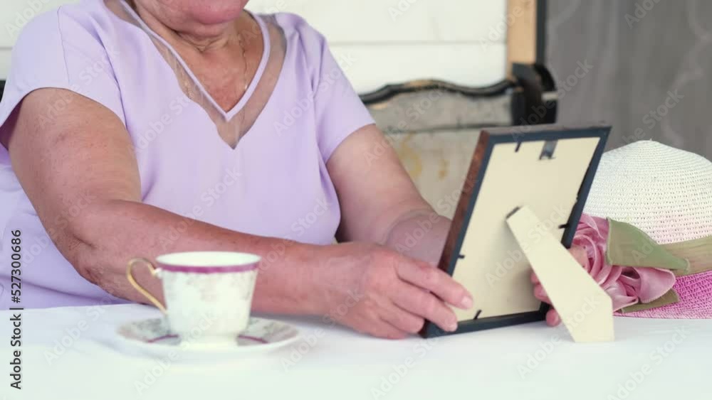 unrecognizable elderly lady sits on the veranda of her house and revises old black and white photographs unrecognizable elderly lady sits on the veranda of her house and revises old black and white photographs