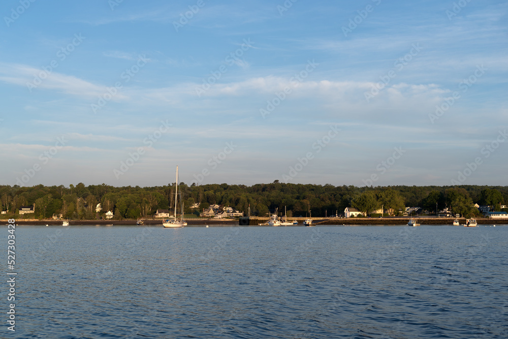 Moored boats at the harbor and pier in Searsport Maine in the early morning light.