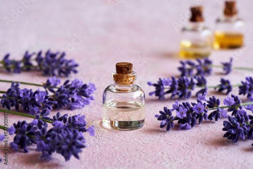 A glass bottle of essential oil with blooming lavender twigs