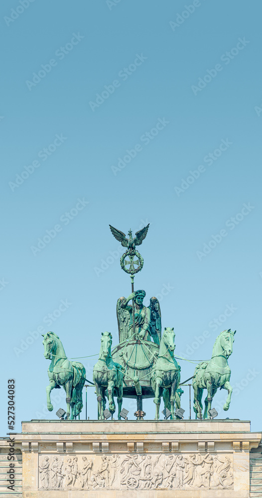 Cover page with Quadriga, four horses lead by Viktoria, Roman goddess of victory at Brandenburg Gate in Berlin historical downtown, Germany, at summer day, blue sky background and copy space.