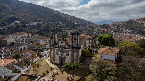 Visão panoramica de igreja em cidade histórica de Ouro Preto Minas Gerais em meio a montanhas e céu nublado construções e casas antigas ao fundo photo