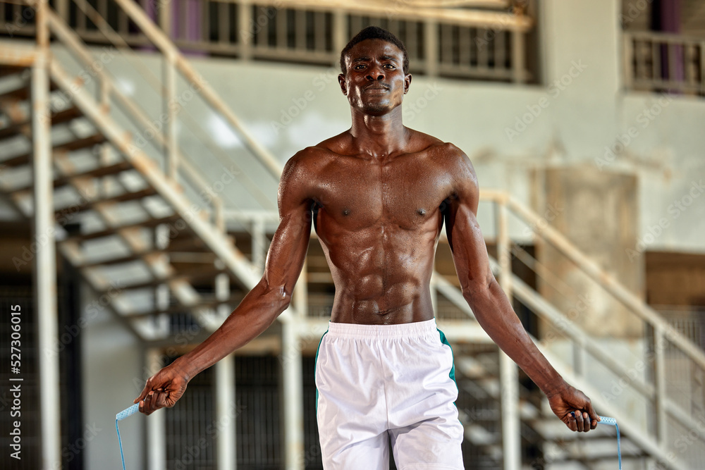 Black young sportsman working out with jumping rope outdoors