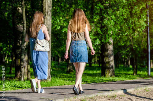 Two girlfriends walk along a path in the Park 