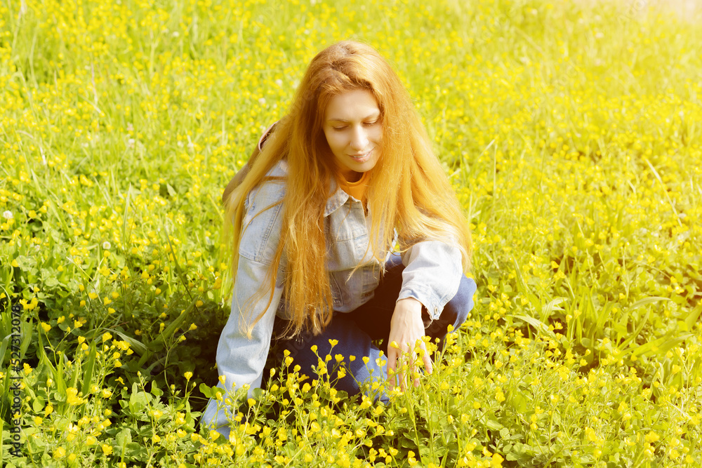 Woman on a yellow ranunculus meadow. A woman sits in a field among yellow buttercups. Portrait of a woman in buttercups Woman on a yellow ranunculus meadow. A woman sits in a field among yellow buttercups. Portrait of a woman in buttercups