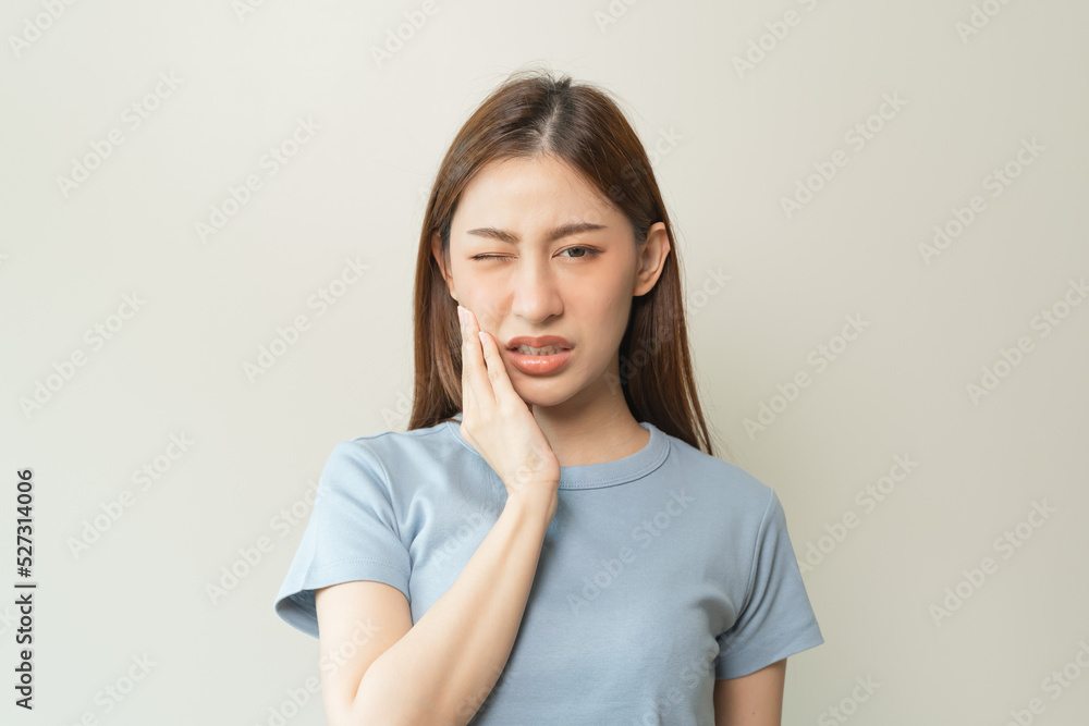 Face expression suffering from sensitive teeth, Asian young woman touching cheek Face expression suffering from sensitive teeth, Asian young woman touching cheek