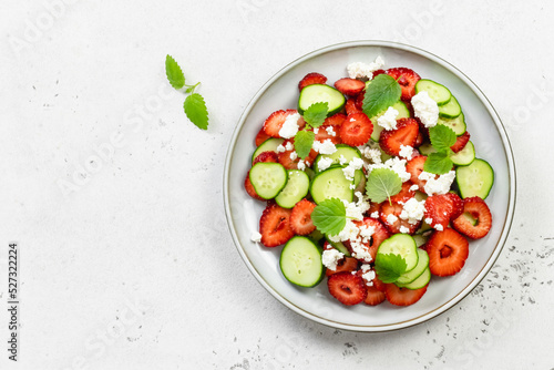 Healthy cucumber strawberry feta cheese salad on plate. Top view, flat lay, copy space.