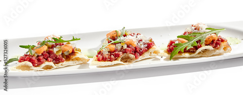 Beef tartare on crispy focaccia isolated on white background. Appetizer from minced meat with spicy sauce on toast. Starter food meat tartare in French style. Contemporary food for restaurant.