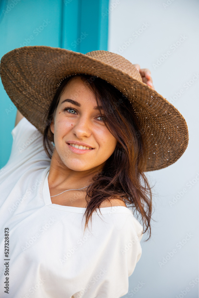 Woman in big straw hat relaxing by entrance door of villa,