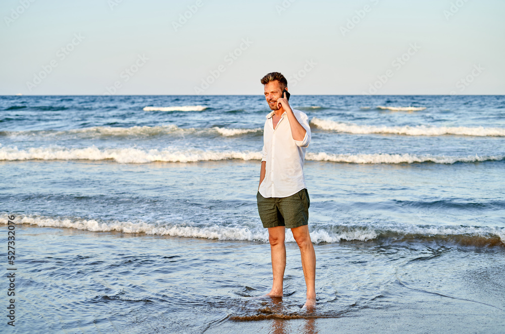 Businessman walking near sea and talking on smartphone Businessman walking near sea and talking on smartphone