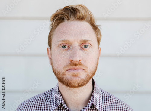 Portrait of serious ginger young adult man looking at camera outdoors