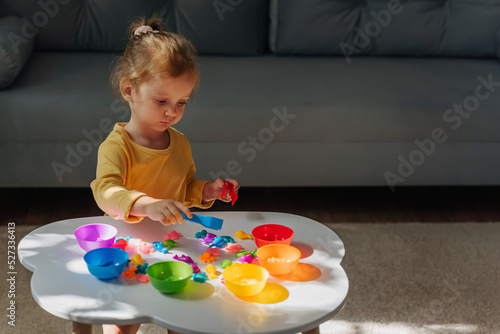 A little girl playing with Colors sorter toy on the table in children room. Educational games for Rainbow Colors sorting. Learning through play. Developing Montessori toddlers activities.