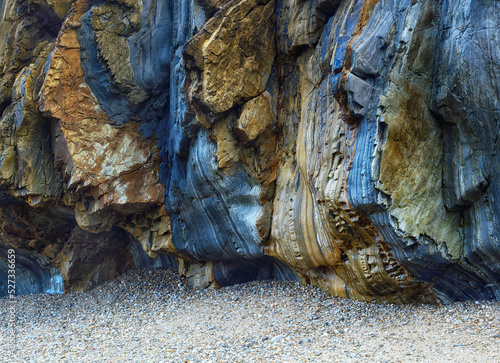 Rough sedimentary rock cliff on beach photo