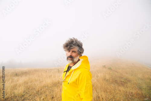 Mature male traveler in foggy valley photo