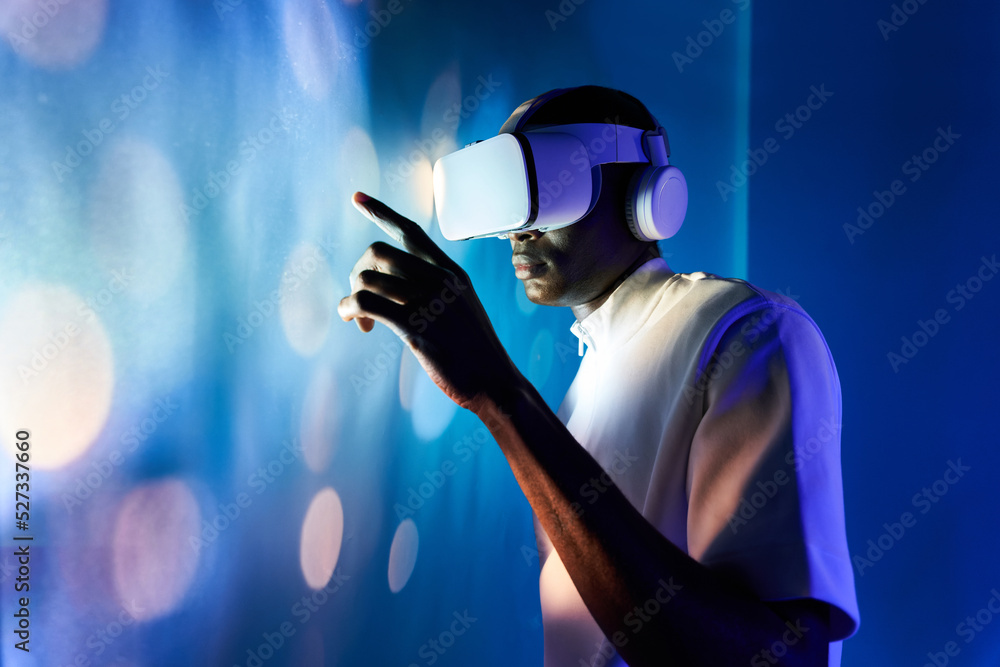 Serious black man touching large screen while exploring virtual reality ...