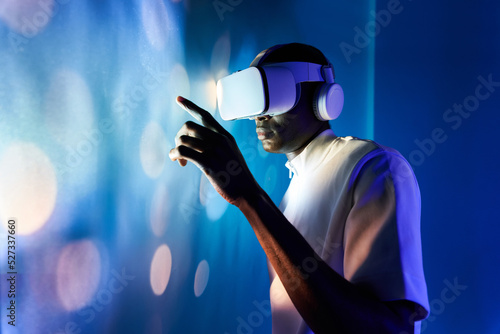 Serious black man touching large screen while exploring virtual reality in modern headset photo