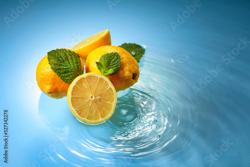 Fototapeta Naklejka Na Ścianę i Meble -  Juicy lemons with mint on a blue background with water splashes.