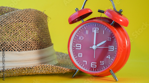 Red clock with hat on yellow background photo