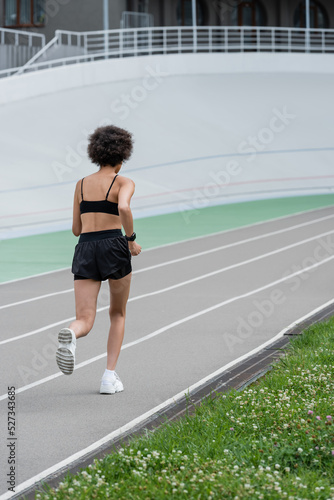 Back view of african american sportswoman running on track of stadium. © LIGHTFIELD STUDIOS