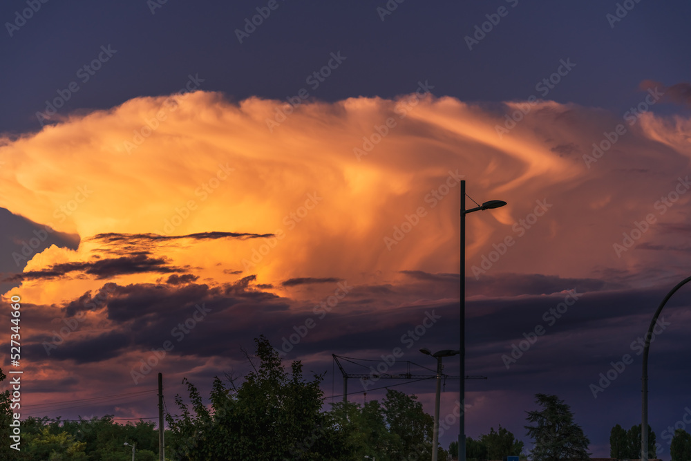 Sunset over trees and electric poles of street lighting on the outskirts of a city in Italy, the sky at sunset, the background image of the evening sky at sunset on a summer day