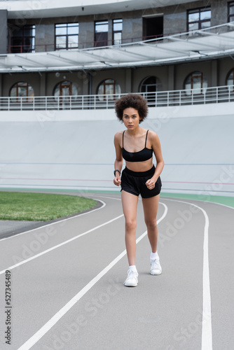 African american sportswoman running on track of stadium.