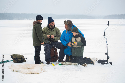 Cheerful male friends enjoying with sons at frozen lake photo