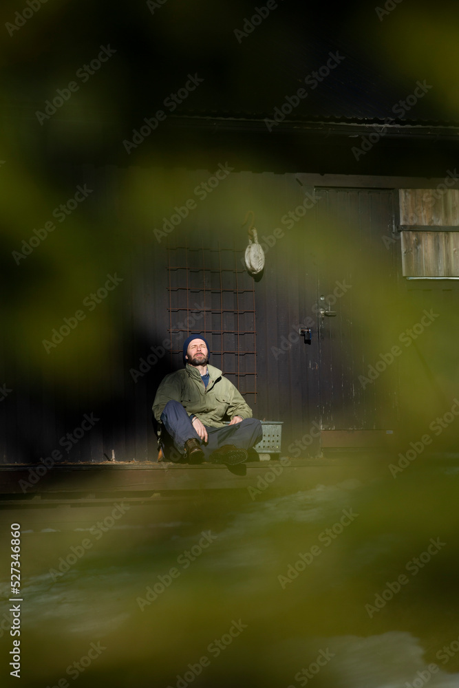 Full length of mature man sitting with eyes closed on porch during sunny day Full length of mature man sitting with eyes closed on porch during sunny day