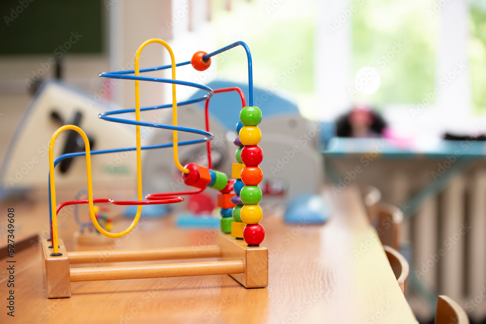 Children's toy labyrinth, maze on a metal spiral with ball, cylinder, cube on a wooden stand close-up