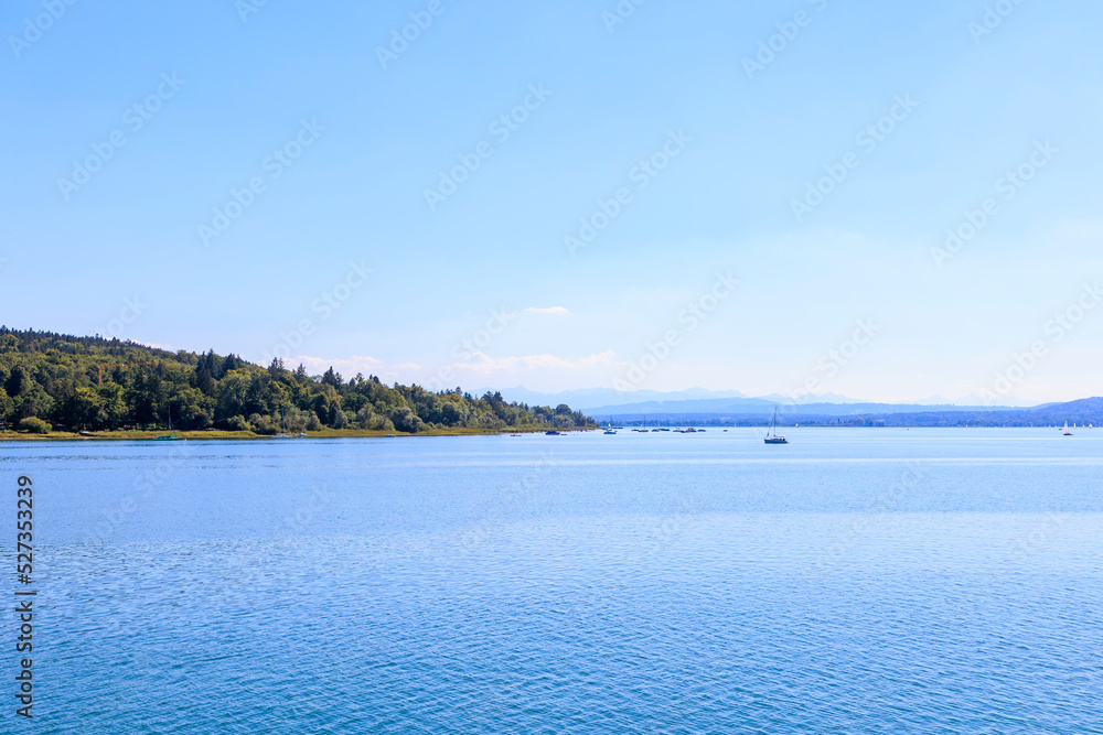 View over Ammersee lake in Bavaria with sailboats on the water and Ammergau Alps in the background View over Ammersee lake in Bavaria with sailboats on the water and Ammergau Alps in the background