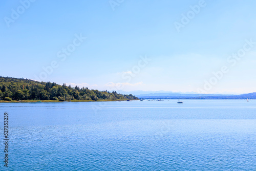 View over Ammersee lake in Bavaria with sailboats on the water and Ammergau Alps in the background