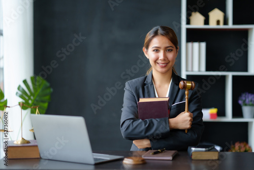 Принти на полотні Beautiful Asian woman lawyer sitting at a table smiling happy with a laptop computer with law books hammer and scales hammer and scale