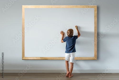 Caucasian boy standing writing messages and texts on a large white board. Mockup for inserting phrases and advertisements