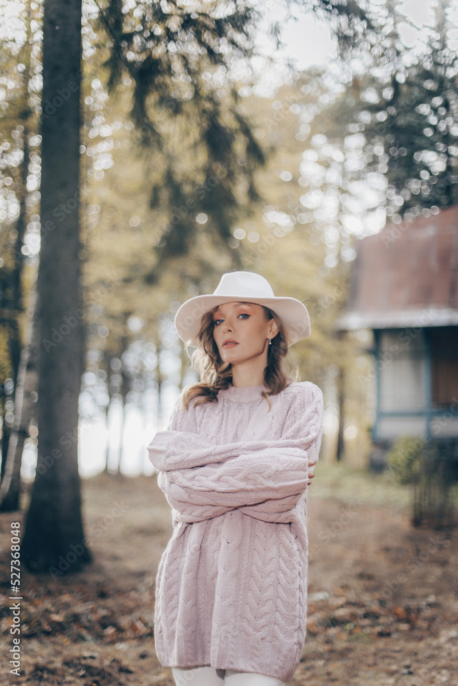 blonde in a white hat walks in the old park on an autumn day