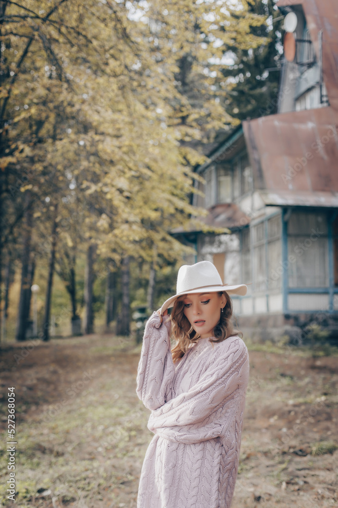 blonde in a white hat walks in the old park on an autumn day