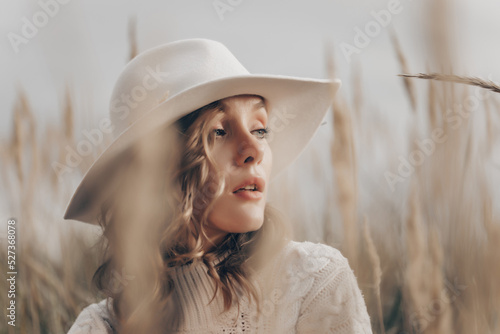 blonde girl in a white hat walks along the seashore on an autumn day