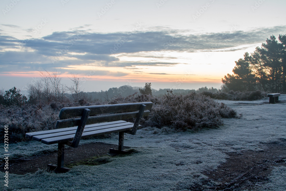 A cold and frosty bench in Winter at sunrise. Mental health awareness.