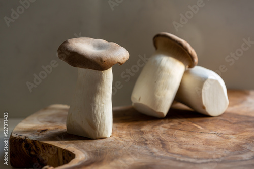 A trio of king oyster mushrooms shot in natural morning light on a wooden baord photo