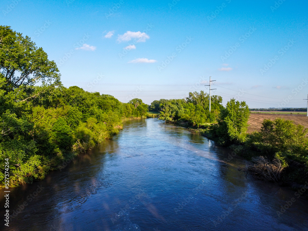 Rural Nemaha river with high waters flowing through farmland in Nebraska