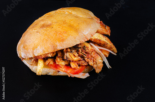 Chicken doner kebab on hamburger bun. Doner kebab in bread on wooden board on black background.
