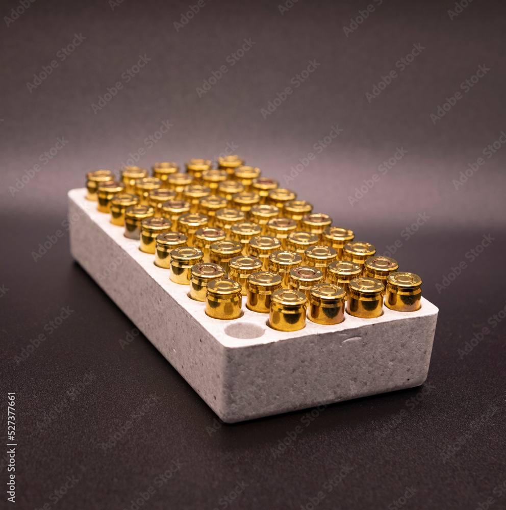 9mm cartridges bullets with one gone or used in a white container on a black background. 9mm cartridges bullets with one gone or used in a white container on a black background.