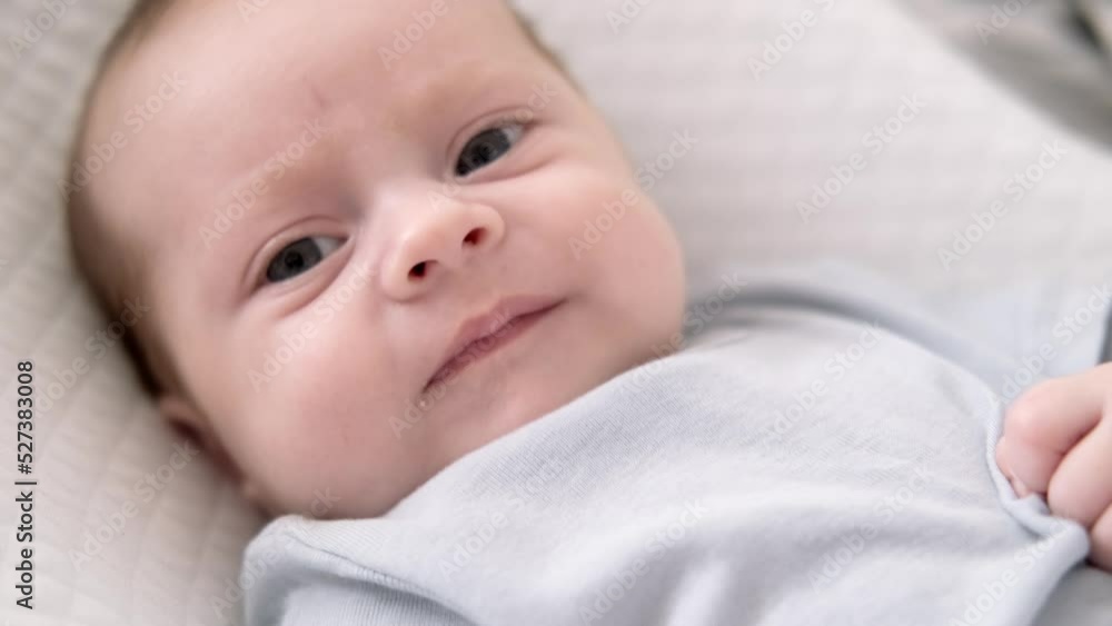 Dissatisfied, crying, upset, sad Newborn baby boy lying in nursery cocoon with blue clothes on bed in bedroom at home, baby morning Dissatisfied, crying, upset, sad Newborn baby boy lying in nursery cocoon with blue clothes on bed in bedroom at home, baby morning